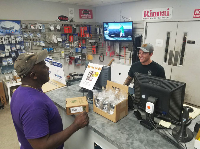 Plumbing service counter teammate smiling while helping a plumbing contractor